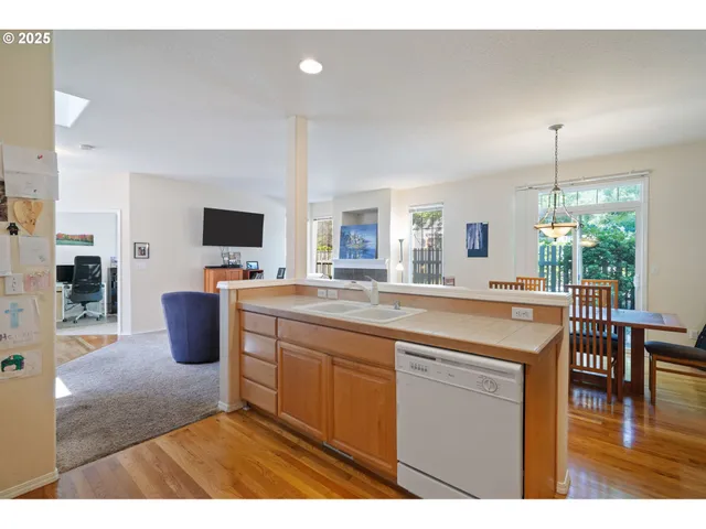 a open kitchen with kitchen island granite countertop a sink counter top space and a view of living room