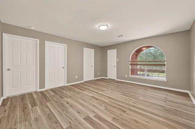 a view of an empty room with wooden floor and a window