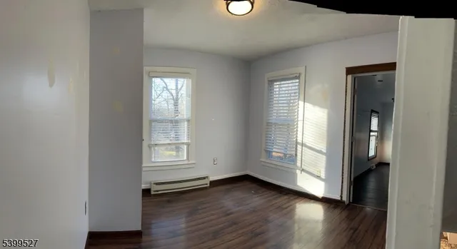 an empty room with wooden floor cabinet and windows