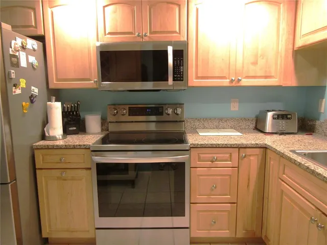 a kitchen with granite countertop white cabinets stainless steel appliances and a sink