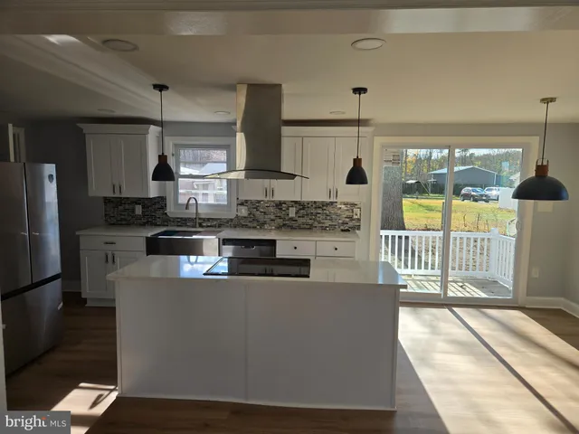 a kitchen with stainless steel appliances granite countertop a stove a refrigerator a sink and a dining table with wooden floor