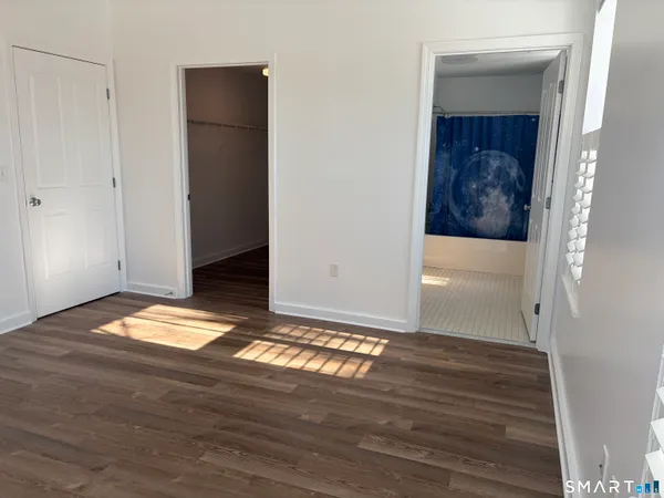 a view of empty room with wooden floor and closet