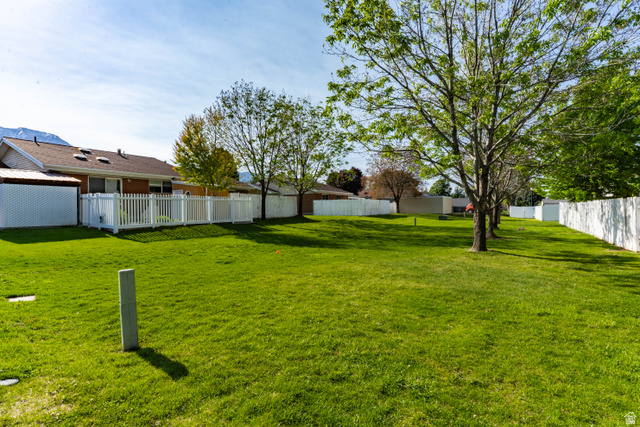728 400 East Orem, UT 84097 - Photo 27 of 30 Expansive grass yard bordered by white fencing, featuring mature trees and a distant mountain backdrop