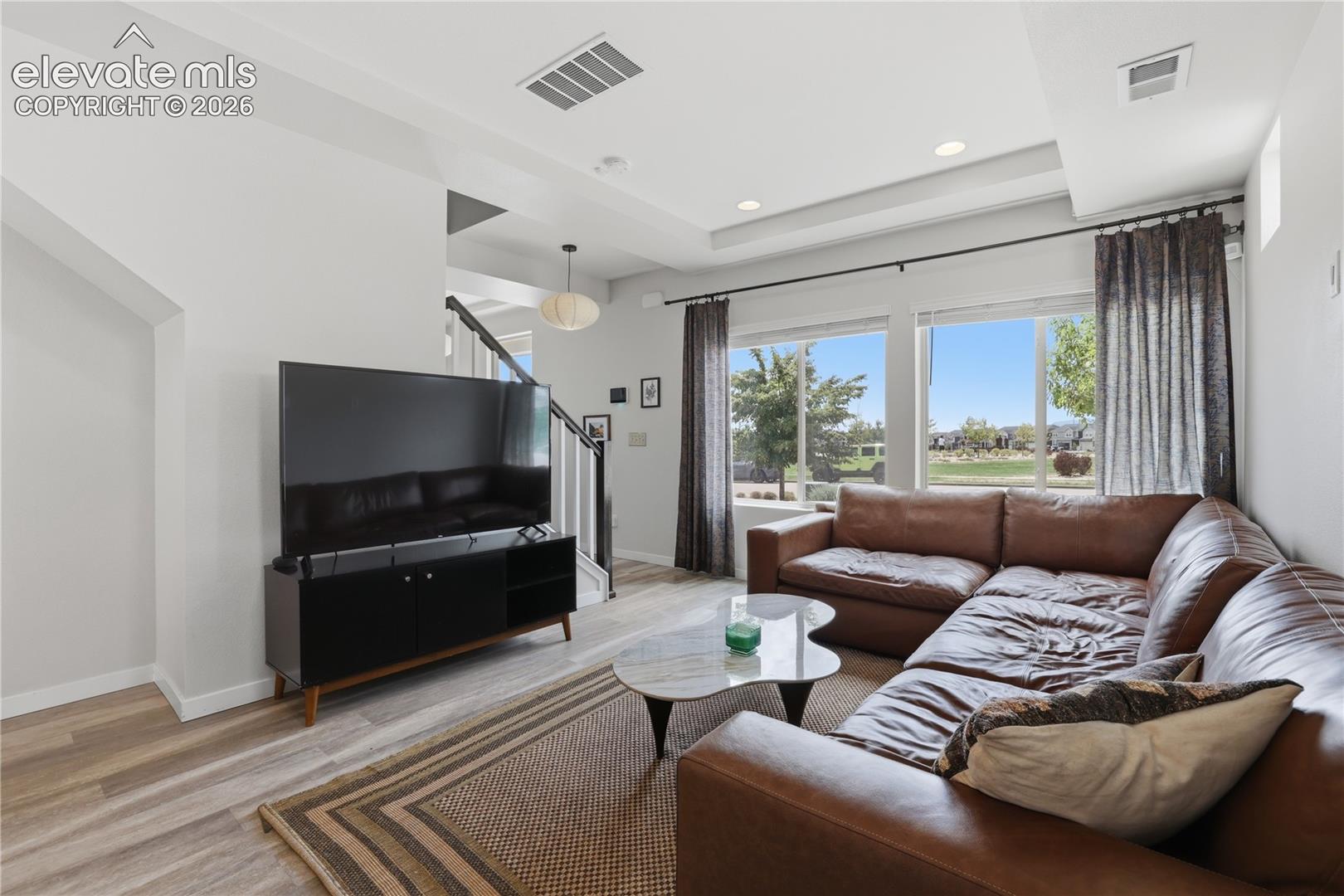 6008 Ashmore Road Colorado Springs, CO 80927 - Photo 10 of 48 Spacious living area featuring large windows, wood-finish flooring, recessed lighting, and a tray ceiling