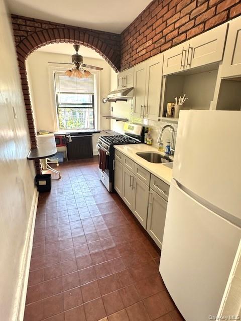 45-47 43rd Street Queens, NY 11104 - Photo 16 of 26 Kitchen with freestanding refrigerator, stainless steel gas range oven, light stone countertops, a ceiling fan, and under cabinet range hood