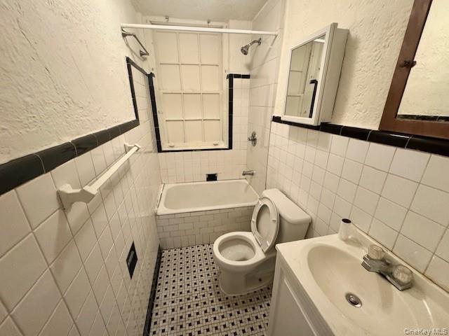 45-47 43rd Street Queens, NY 11104 - Photo 22 of 26 Bathroom featuring tile walls, a textured wall, bathtub / shower combination, vanity, and tile patterned flooring