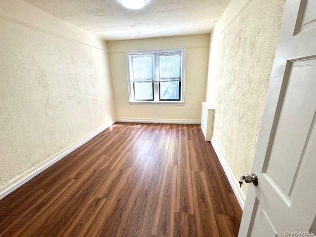 45-47 43rd Street Queens, NY 11104 - Photo 5 of 26 Unfurnished room with a textured wall, dark wood-type flooring, and a textured ceiling