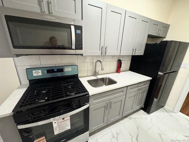 45-47 43rd Street Queens, NY 11104 - Photo 9 of 26 Kitchen with stainless steel appliances, gray cabinets, light marble finish flooring, and decorative backsplash