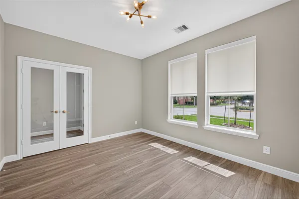 a view of an empty room with a window and wooden floor