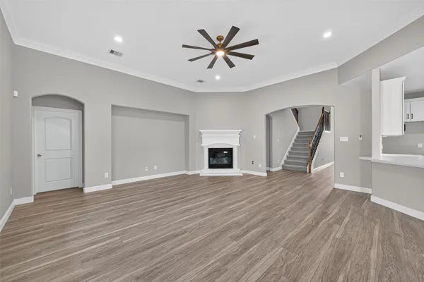 a view of an empty room with wooden floor and a ceiling fan