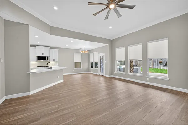 a view of an empty room with kitchen and window