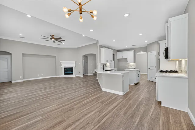 a large white kitchen with kitchen island a sink stainless steel appliances and cabinets