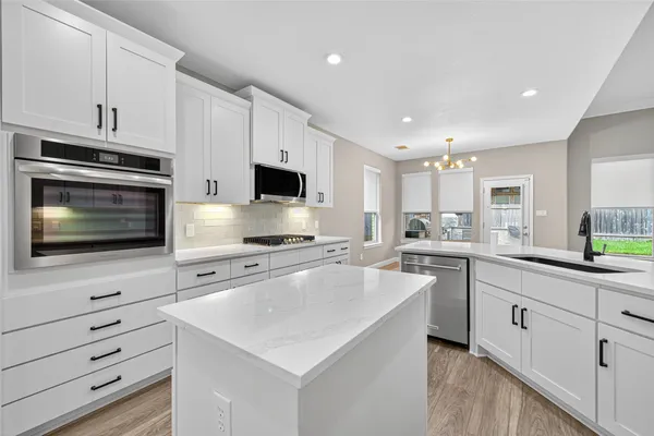 a kitchen with cabinets appliances a sink and a counter top space