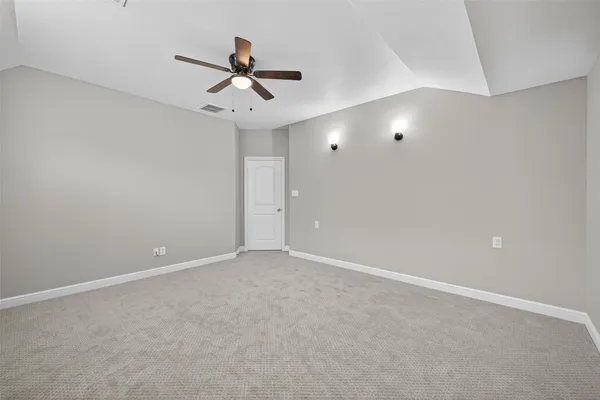 an empty room with a chandelier fan and windows