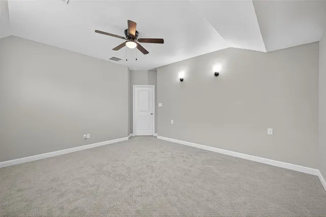 an empty room with a chandelier fan and windows
