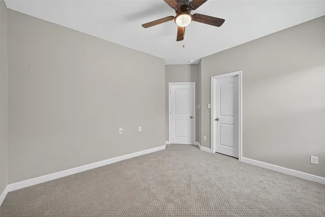 an empty room with ceiling fan and window