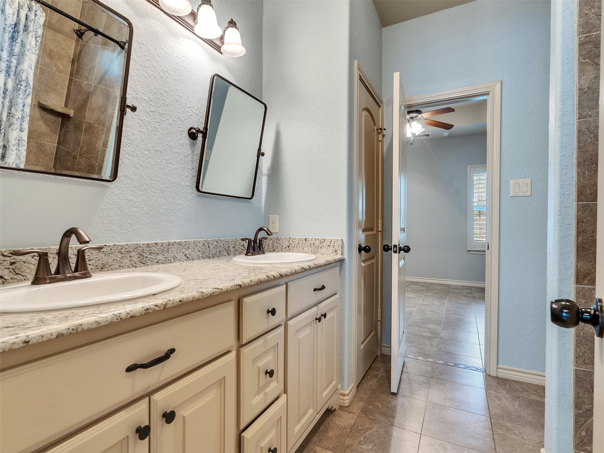 18005 Cindy Lane Conroe, TX 77302 - Photo 30 of 49 This bathroom features a dual-sink vanity with granite countertops and classic cabinetry. It has a neutral color scheme, modern fixtures, offering a spacious and functional layout.