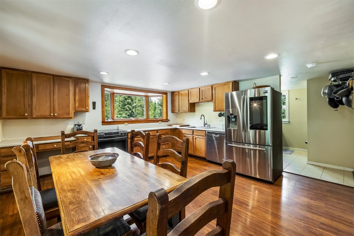 5115 Montezuma Road Montezuma, CO 80435 - Photo 13 of 35 a kitchen with stainless steel appliances granite countertop a refrigerator a stove a sink a dining table and chairs with wooden floor
