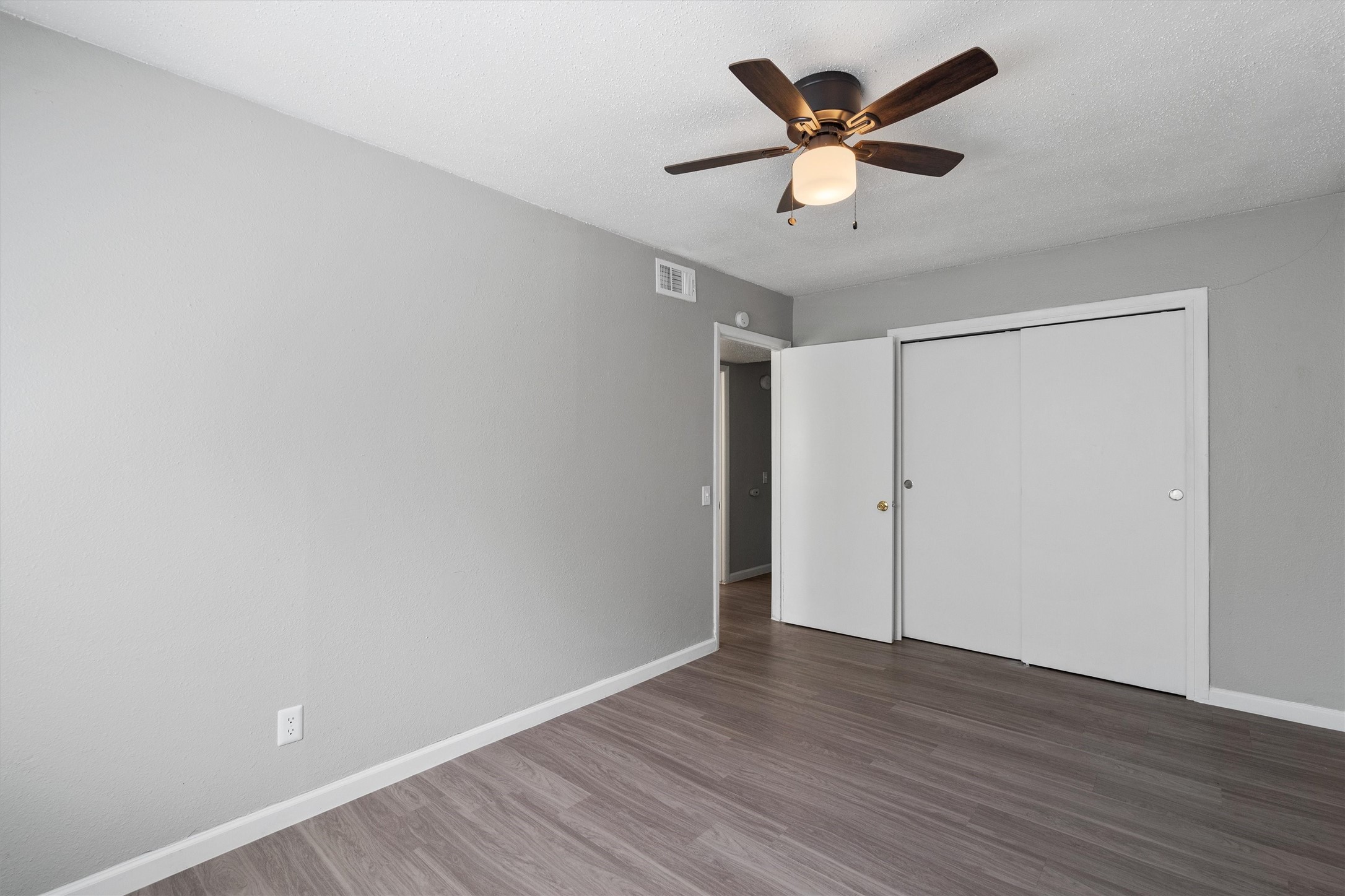 2501 Manor Circle, Unit B Austin, TX 78723 - Photo 11 of 17 an empty room with wooden floor and ceiling fan