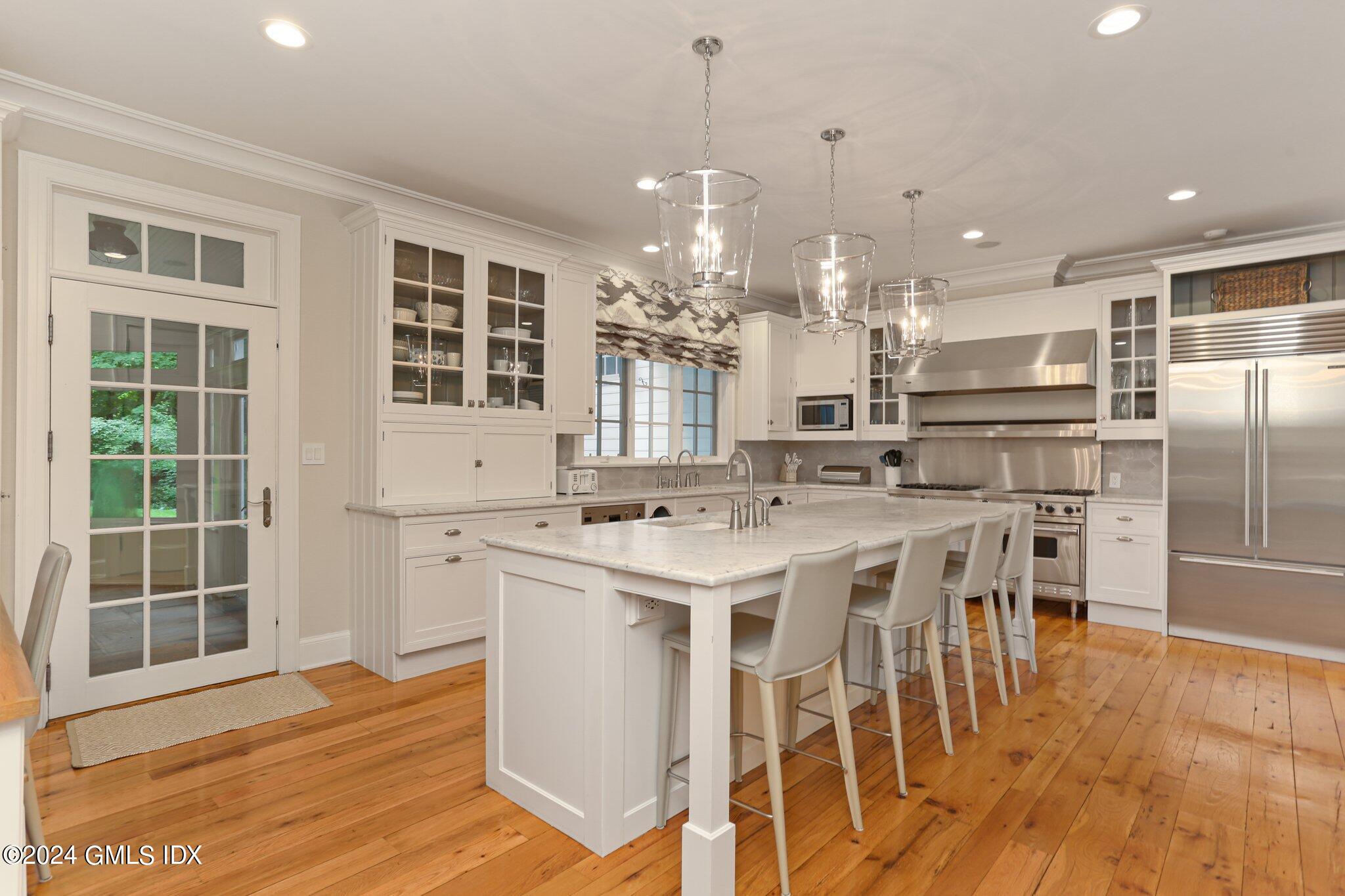 68 Rock Maple Road Greenwich, CT 06830 - Photo 16 of 46 a kitchen with stainless steel appliances a dining table chairs stove and cabinets