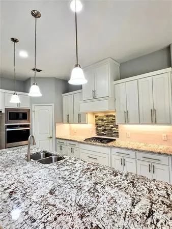 a kitchen with stainless steel appliances granite countertop a stove a sink and a oven