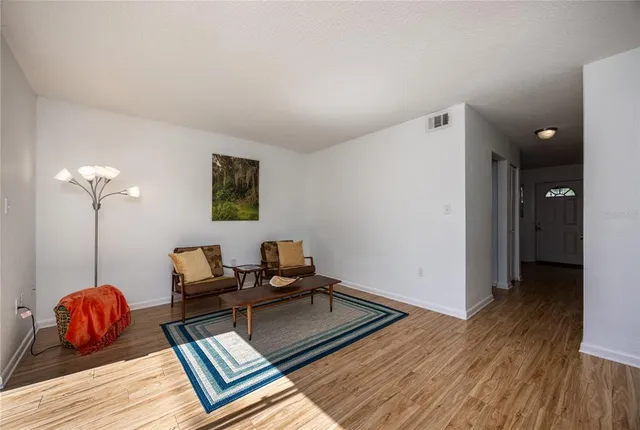 a living room with couch chairs and a wooden floor