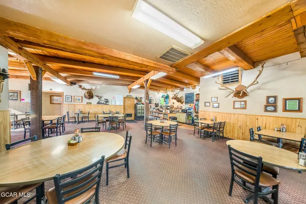 a dining hall with stainless steel appliances refrigerator a dining table and chairs with wooden floor