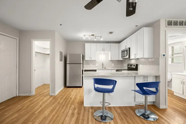 a kitchen with stainless steel appliances granite countertop a refrigerator a stove a sink dishwasher a stove and a dining table with wooden floor