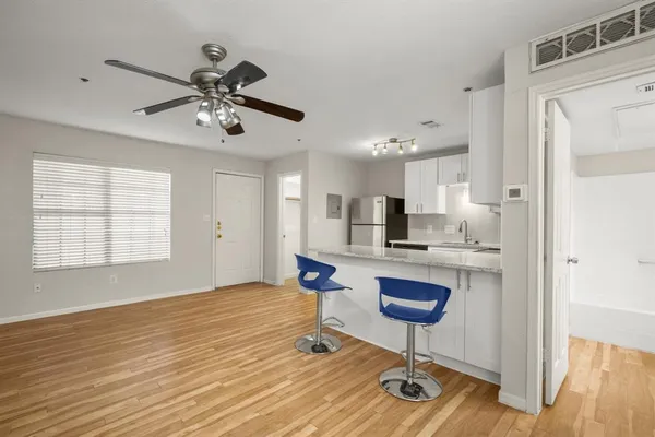 a living room with kitchen island granite countertop furniture wooden floor and a rug
