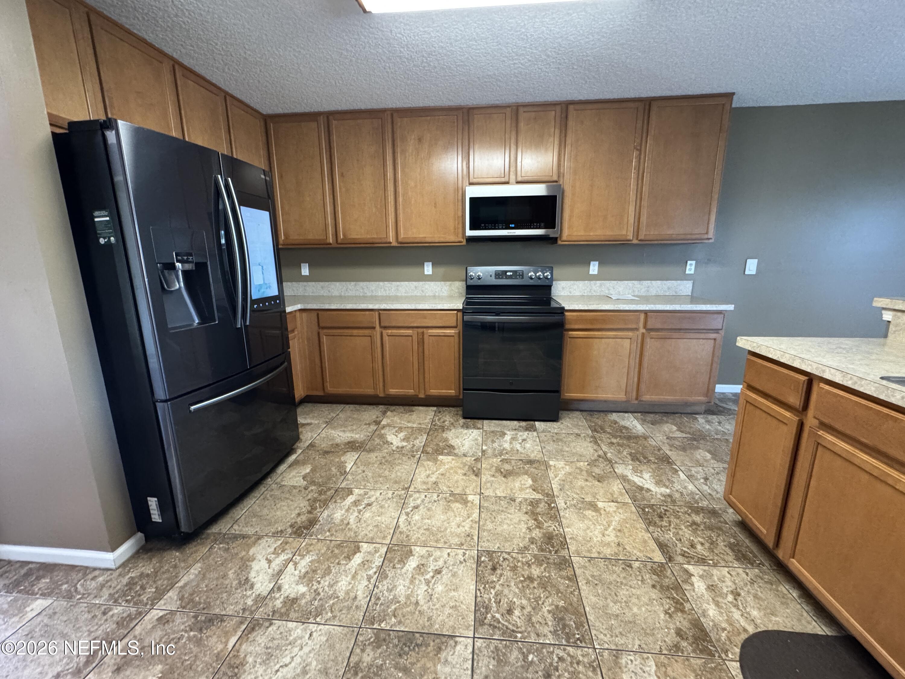 2725 Ravine Hill Drive Middleburg, FL 32068 - Photo 3 of 23 a kitchen with granite countertop a refrigerator and a stove top oven