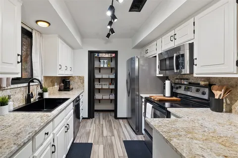 a kitchen with stainless steel appliances granite countertop a stove top oven a sink dishwasher and cabinets with wooden floor