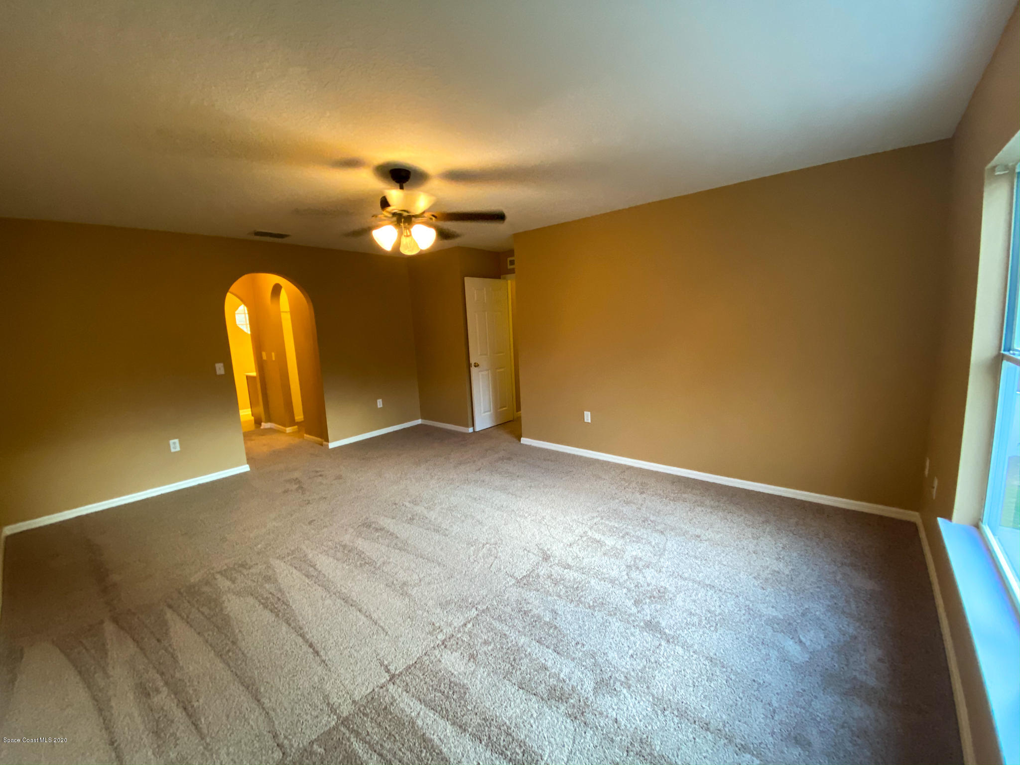 6150 Degan Road Cocoa, FL 32927 - Photo 31 of 48 an empty room with a chandelier fan and windows