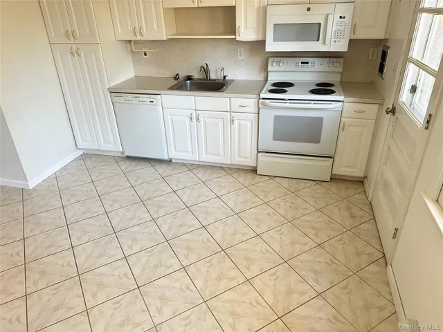a kitchen with white cabinets a sink a stove and a refrigerator