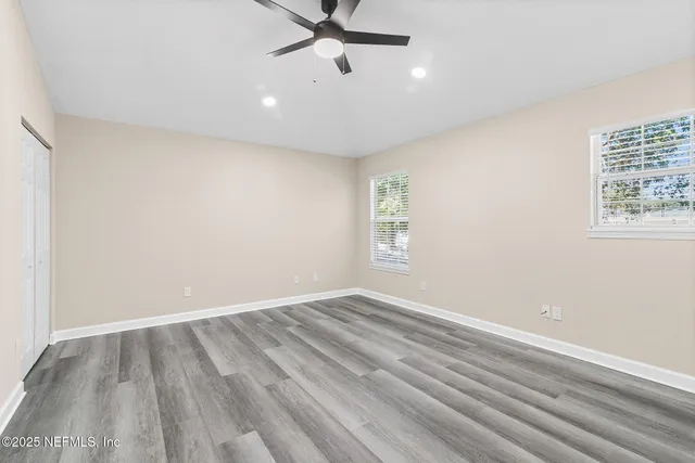 an empty room with windows and fan