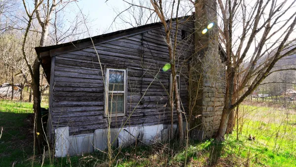 a view of a patio with table and chairs under an umbrella with large trees