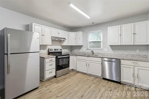 a kitchen with granite countertop a refrigerator stove top oven and sink