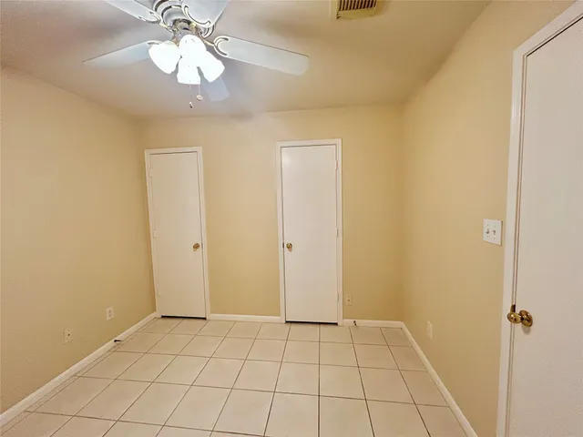 a view of an empty room and chandelier fan