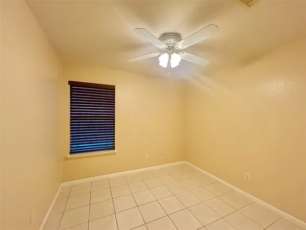 a view of an empty room and chandelier fan