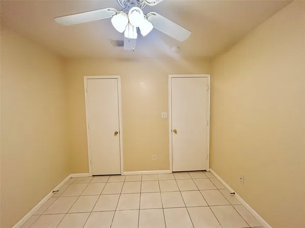 a view of an empty room and chandelier fan