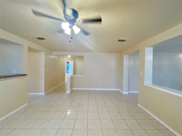 a view of an empty room with a chandelier fan