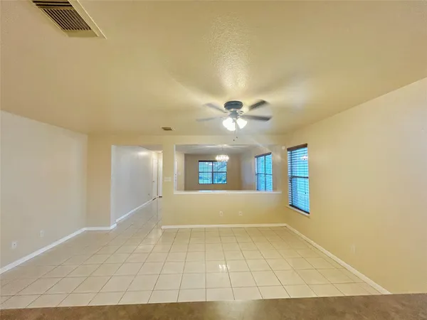 a view of an empty room with window and chandelier fan