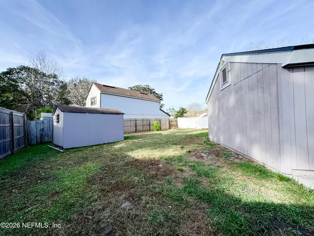 a view of a yard in front of a house with large trees