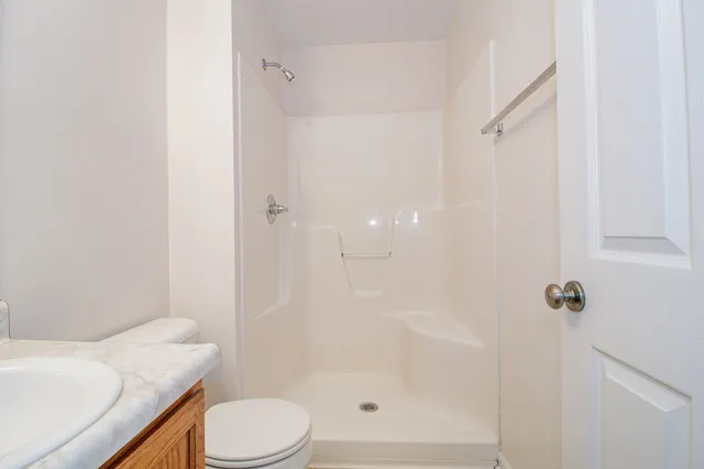 an empty room with chandelier fan and windows