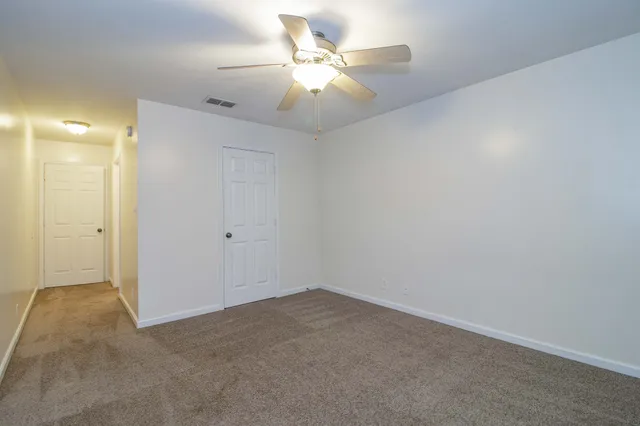 an empty room with a chandelier fan and closet area