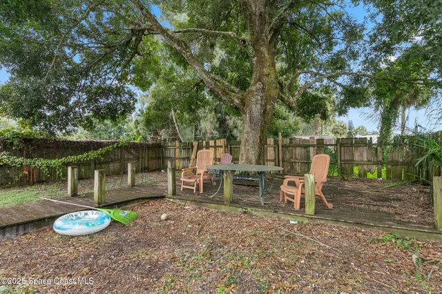 a view of a backyard with table and chairs a fire pit and large trees