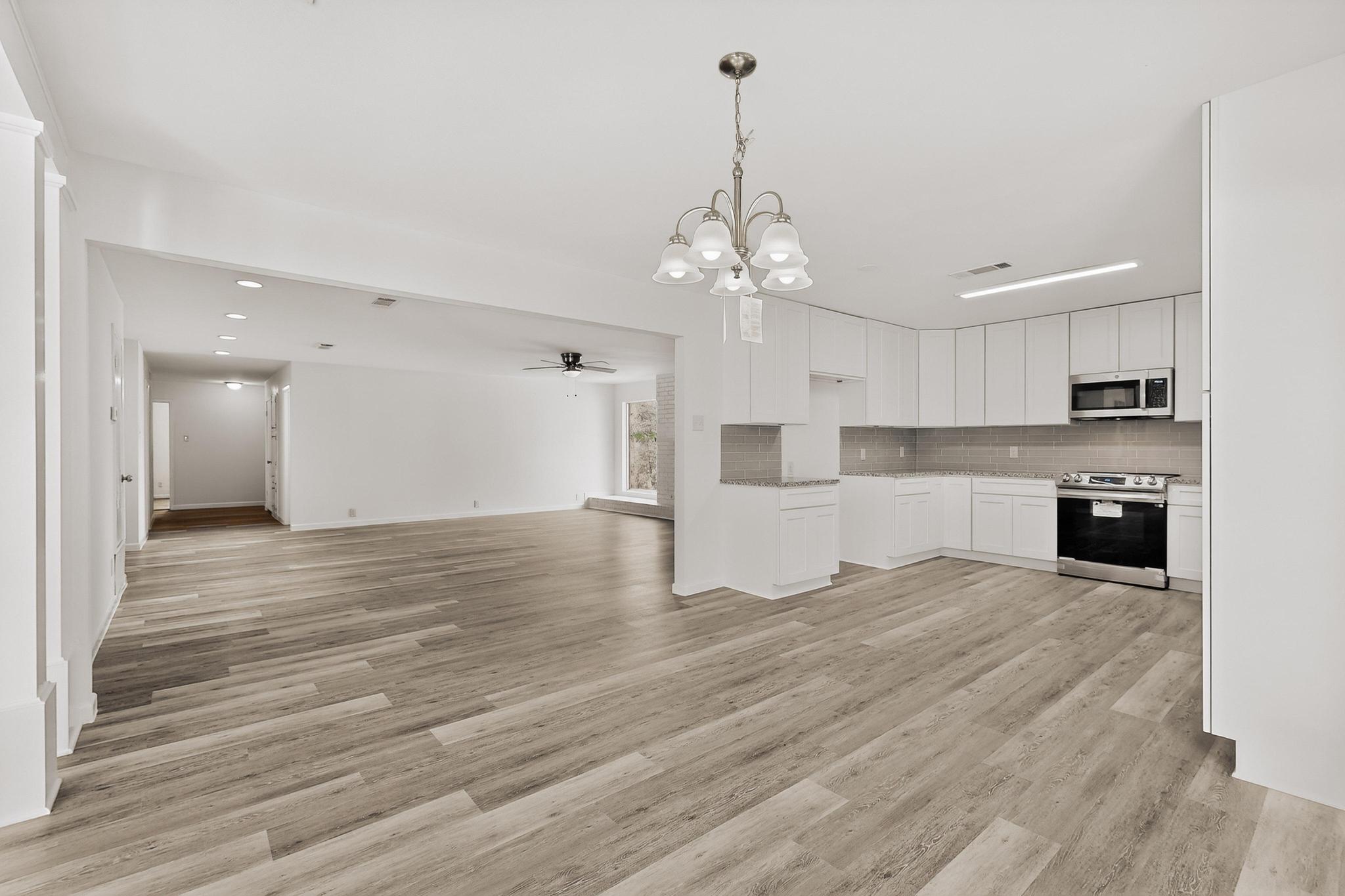 812 George Street Taylor, TX 76574 - Photo 33 of 34 Kitchen featuring hanging lights, stainless steel appliances, white cabinets, open floor plan, and a ceiling fan