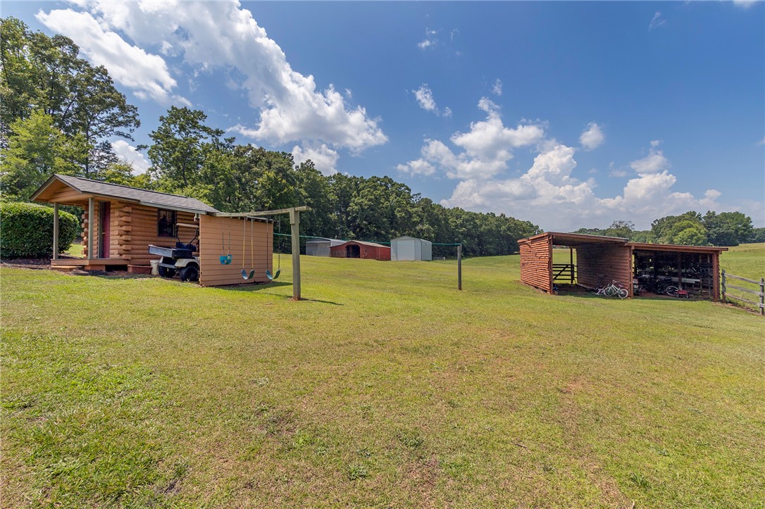 911 State Rd S-4-203 Belton, SC 29627 - Photo 44 of 49 Rural retreat with a charming log cabin and useful outbuildings nestled in a wide open field.