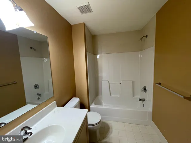 an empty room with chandelier fan and windows