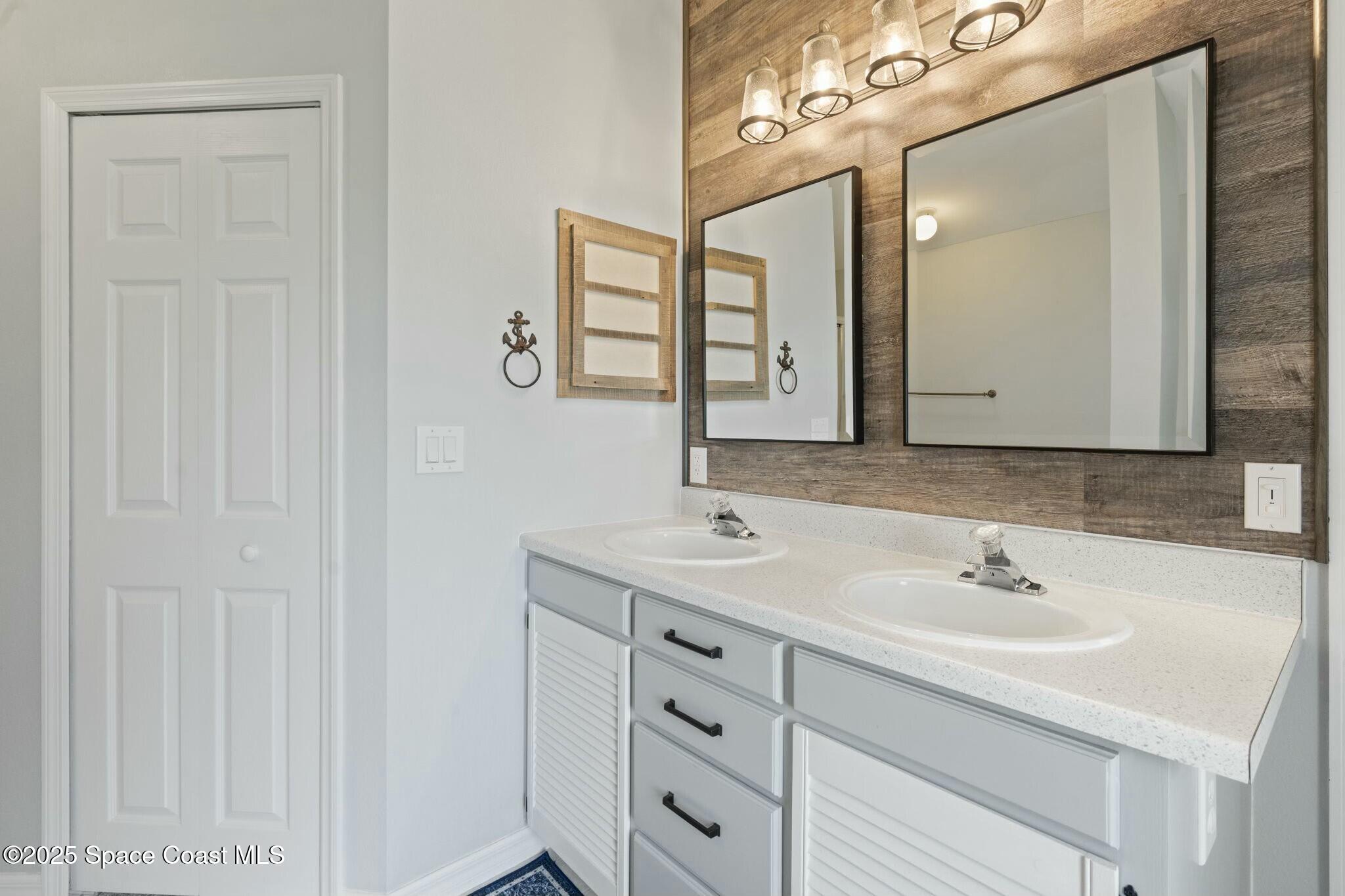 2405 Bayhill Drive Melbourne, FL 32940 - Photo 12 of 36 a bathroom with a double vanity sink and a mirror