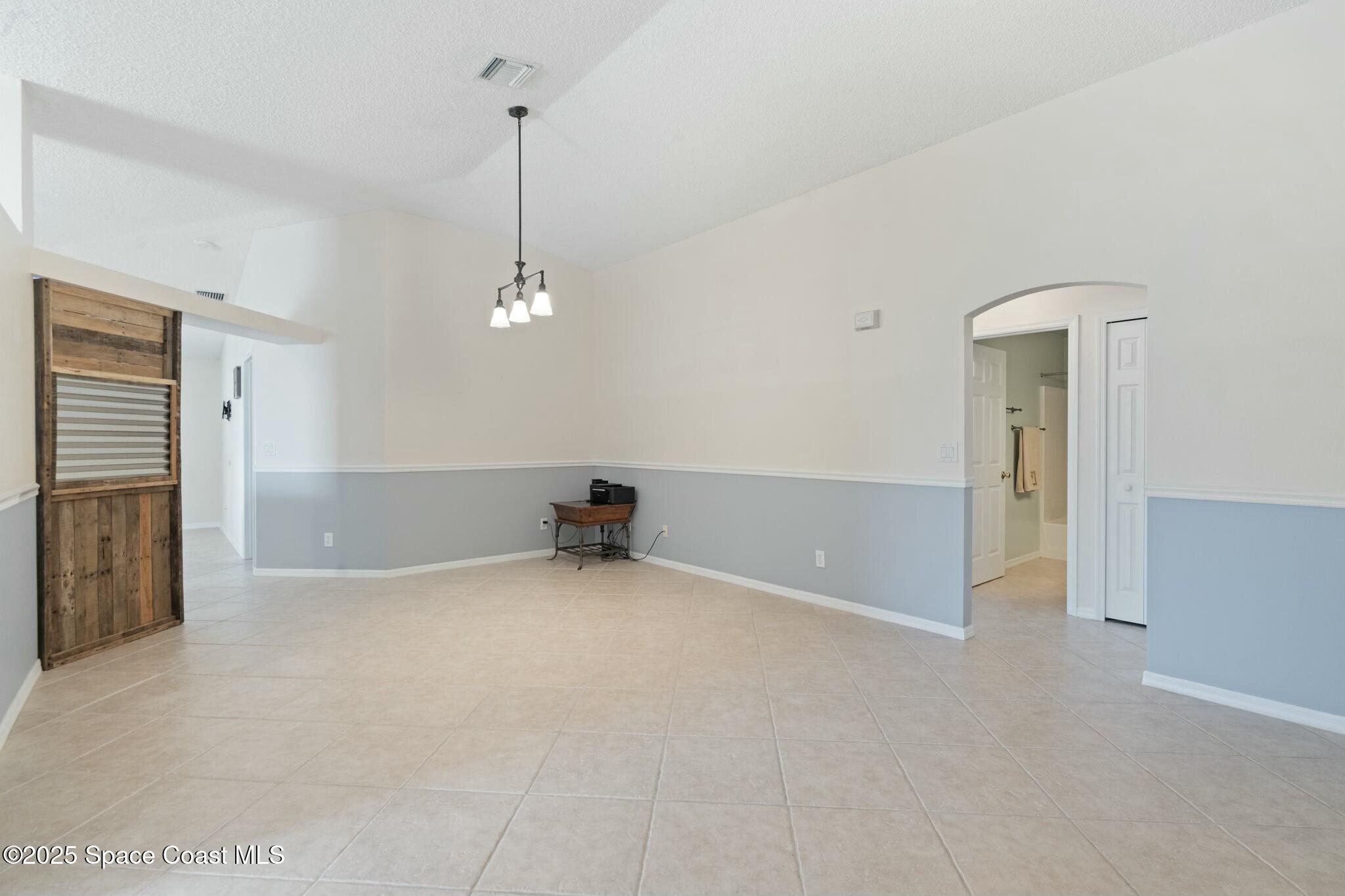 2405 Bayhill Drive Melbourne, FL 32940 - Photo 15 of 36 an empty room with chandelier fan and windows